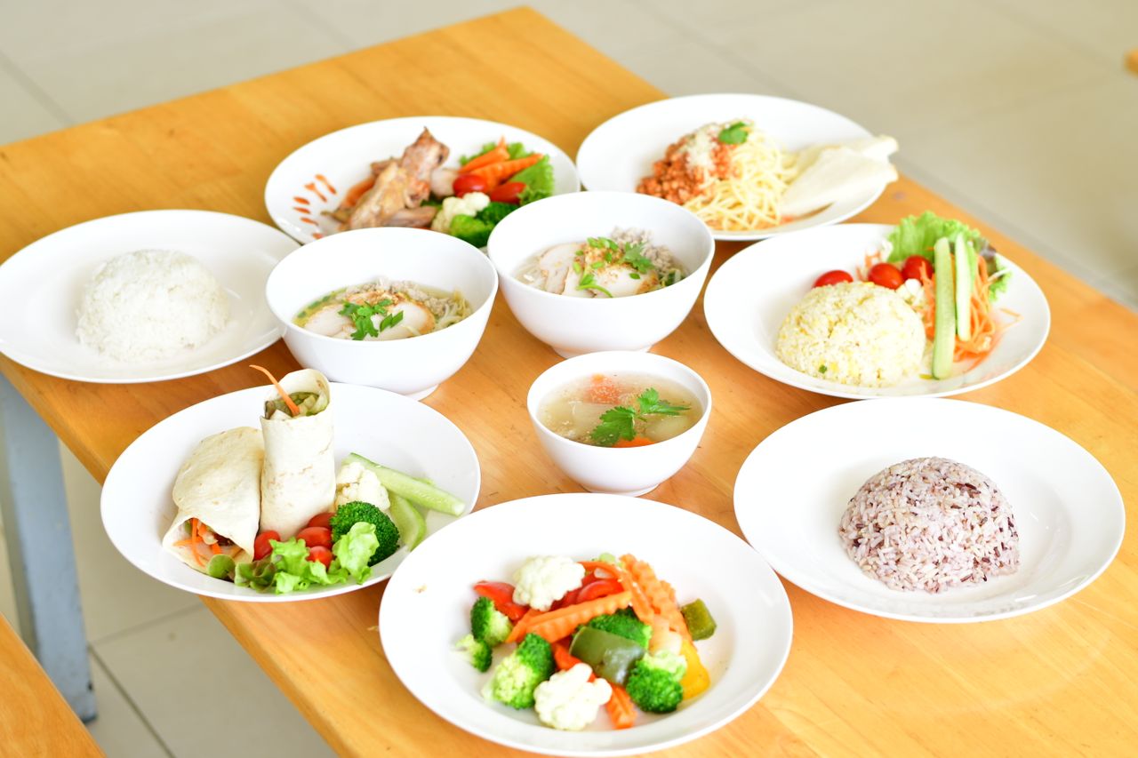 our-experience A variety of healthy dishes including rice, soup, and vegetables served on a wooden table.