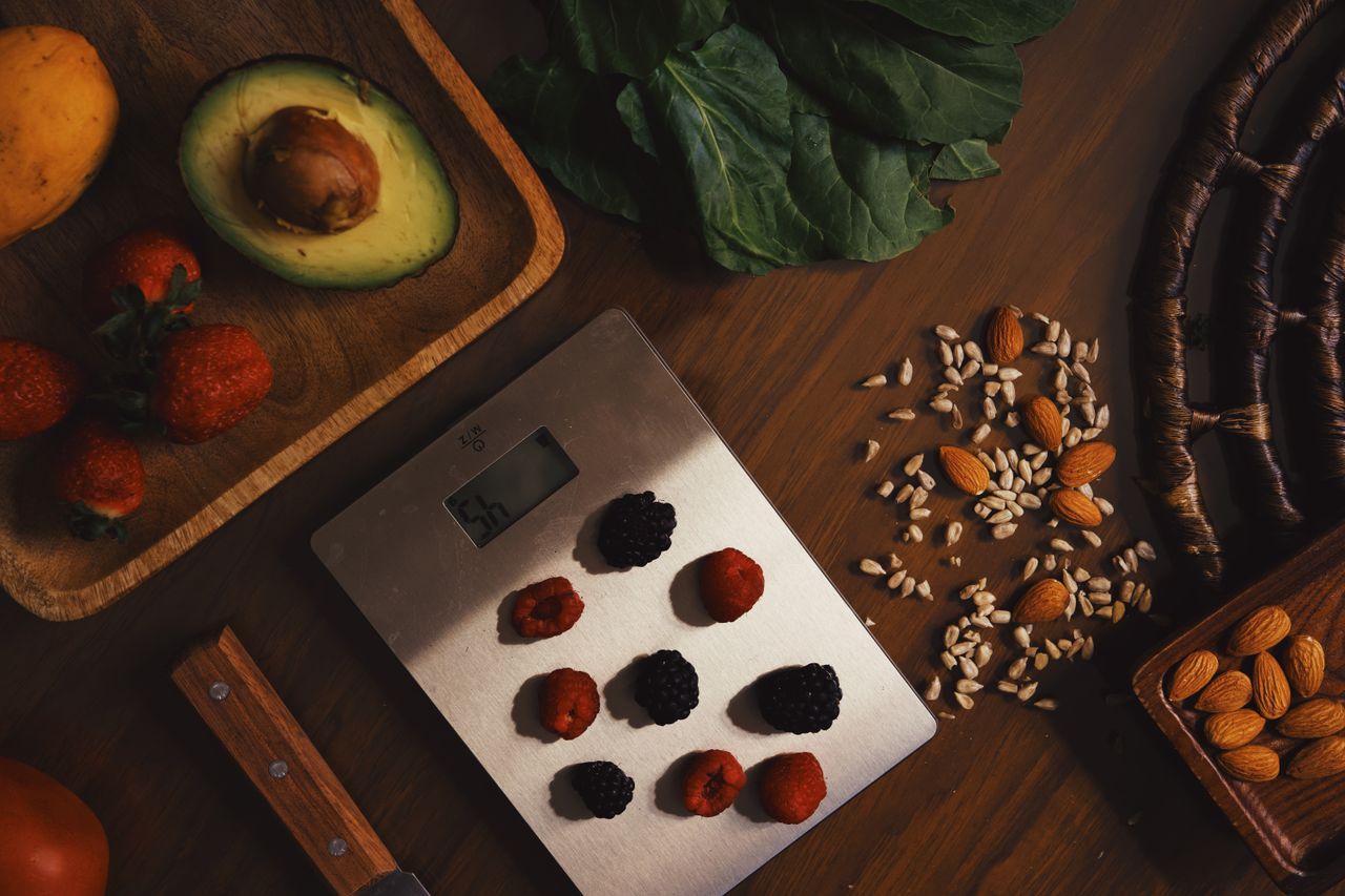 about-02 Top view of composed raw almond with seeds and avocado on table with berries on scales for cooking healthy dish