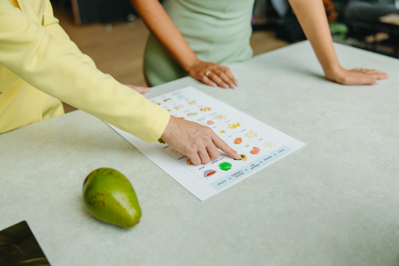 Mastering the First Impression: Your intriguing post title goes here Two adults discussing food options with a chart, highlighting healthy nutrition indoors.